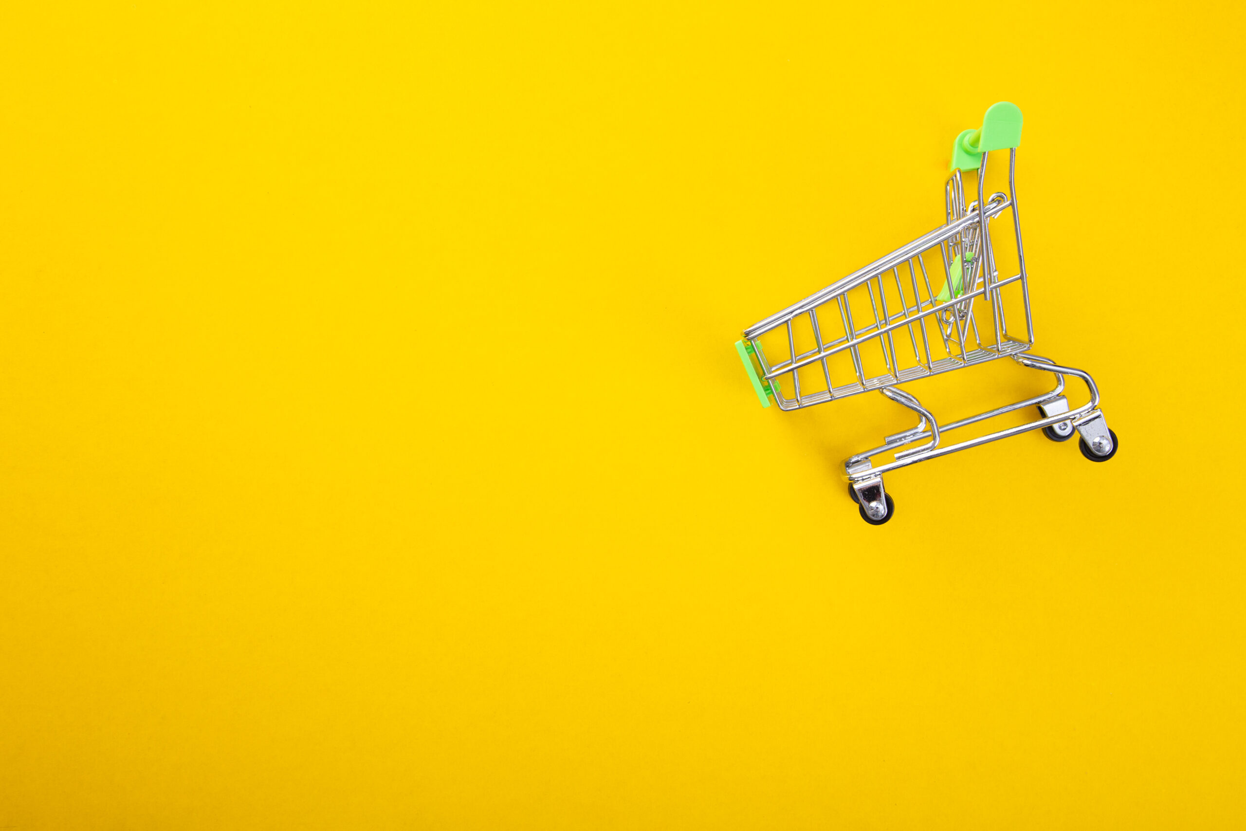 close-up of shopping trolley on yellow background with some copy space